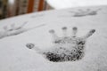 Imprint of one hand on the snow, white texture close to fresh snow on the glass.