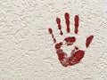 Imprint of a red palm on a white concrete wall