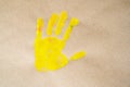 Imprint yellow color child hand isolated on brown paper. Close up. copy space. Creative, funny, artistic and happy