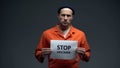 Imprisoned man holding Stop HIV AIDS sign in cell, sexually transmitted disease