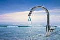 An improbable faucet at the seaside is pouring a drop of water