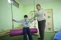 Improving motor control: female therapist helping Down syndrome boy to do exercises at the rehabilitation room