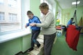 Improving motor control: female therapist helping Down syndrome boy to do exercises at the rehabilitation room