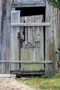 Improvised partially broken old wooden doors with dilapidated boards mounted on backyard structure locked with rusted metal chain