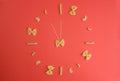Improvised pasta clock on a red background Royalty Free Stock Photo