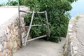 Improvised wooden backyard doors made of wooden sticks surrounded with traditional stone wall and concrete path with fig tree and