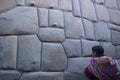 Inca woman looking at angled stones in Hatun Rumiyoc wall, an archeological artefact in Cusco, Peru National heritage object