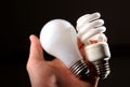 Incandescent and cfl lightbulb in human hand.