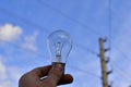 Incandescent lamp in hand on the background of a power line