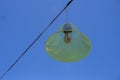 Incandescent lamp with wires running above it and a blue sky background.