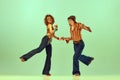 Incendiary dance. Emotional man and woman in retro style clothes dancing disco dance over green background. Concept of Royalty Free Stock Photo