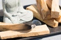 Incense burning. Closeup view of burning palo santo stick with Buddha statue. Zen concept, room fumigation ritual Royalty Free Stock Photo