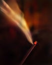 Incense burning with smoke at night. Dark background. Selective focus on red head of incense or agarbatti