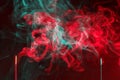 Incense smoke. smoldering piece of wood . incense sticks in blue lighting. aromatic smoke . Green and red colour Royalty Free Stock Photo