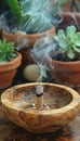 An Incense Stick Is Burning In A Wooden Bowl On A Blurred Background Of House Plants