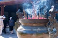 Incense sticks burning in a big pot as temple offering. Vietnam. Incidental people in the background