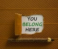 Inclusion and belonging symbol. Words `You belong here` appearing behind torn brown paper. Beautiful brown background. Business,