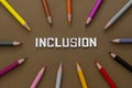 Inclusion word with colorful pencils over brown background. Equality, community integration concept. Top view