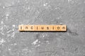 Inclusion word written on wood block. Inclusion text on cement table for your desing, concept Royalty Free Stock Photo