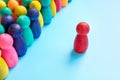 Inclusive Leadership concept. A red figurine in front of a crowd of colorful figurines.