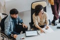 Inclusive office environment and teamwork between handicapped man in wheelchair and brunette woman. Royalty Free Stock Photo