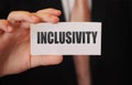 Inclusivity written on a card in businessman`s hand. Diversity and tolerance in workplace business teamwork social wellfare