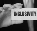 Inclusivity written on a card in businessman& x27;s hand. Diversity and tolerance in workplace business teamwork social