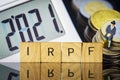 Income Tax Campaign 2021. Taxman sitting on coin stack. IRPF sign Macro Royalty Free Stock Photo