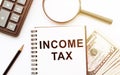 Income Tax - notebook on desk with dollars, magnifier, calculator and pencil in the office Royalty Free Stock Photo