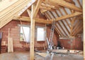 Incomplete attic with roof trusses, wooden roof beams, braces and windows inside. Converting an attic into a room