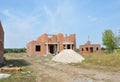 Incomplete Brick House Construction with Doorway Columns and Windows Frame, Pile of Sand
