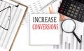 INCREASE CONVERSIONS text on notebook with clipboard and calculator on a chart background Royalty Free Stock Photo