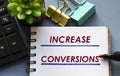 INCREASE CONVERSIONS words is written in a notebook with a marker, calculator, clamps and cactus