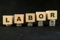 Increase in labor cost concept. Wooden blocks with increasing stack of coins in black background. Royalty Free Stock Photo