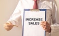 Increase sales inscription text written on white paper in businessman hands