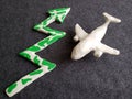 white plasticine airplane and arrow up in green with white on dark gray background