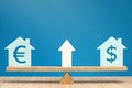 Increasing the cost of housing. House models with dollar and euro symbols balance on the scales. Banner on the theme of