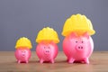 Increasing Pink Piggy Banks With Yellow Hard Hat