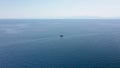 Incredible aerial shot in the open sea with a view of a white boat sailing in Aegean Sea, Greece. Royalty Free Stock Photo