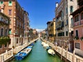 An incredible beautiful view of a canal in Venice, Italy on a bright summer day.  The canal is lined with boats and old colourful Royalty Free Stock Photo