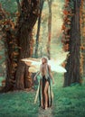 Incredible fairy walks in the autumn forest. A blonde girl with very long hair, unusual styling. Elf in a green dress