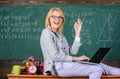 Incredible lecturer lady know how stay in touch modern generation. Woman teacher hold laptop sit table classroom