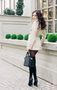 Incredible Long-legged brunette girl with long hair, dressed in a raincoat, high black boots with heels with a handbag Royalty Free Stock Photo