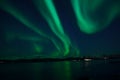 Incredible strong aurora borealis over fjord and snowy mountain Royalty Free Stock Photo