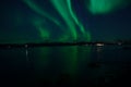 Incredible strong aurora borealis over fjord and snowy mountain Royalty Free Stock Photo