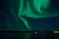 Incredible strong aurora borealis over fjord and snowy mountain Royalty Free Stock Photo