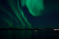 Incredible strong aurora borealis over fjord and snowy mountain Royalty Free Stock Photo