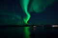 Incredible strong aurora borealis over fjord and snowy mountain Royalty Free Stock Photo