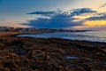 Incredible sunset over coast of Crete with hotels and beaches on the shore. Volcanic rock in the foreground Royalty Free Stock Photo