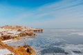 Incredible winter landscape, cold frozen sea covered with small round icicles, blue clear sky against the backdrop of mountains